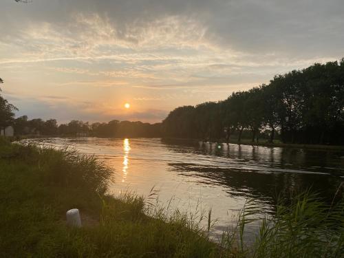 a river with the sun setting in the distance at Vakantiewoning Ten Huyze Bucholt met tuinsauna in Bocholt
