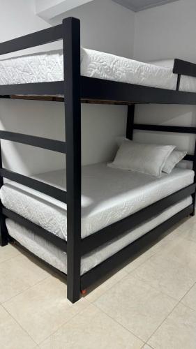 a black bunk bed with white sheets on it at Mami yola 2 in Valledupar