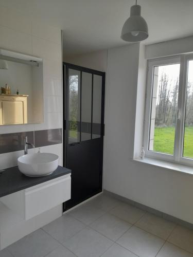 a white bathroom with a sink and a window at La grange aux oiseaux in Beaulieu