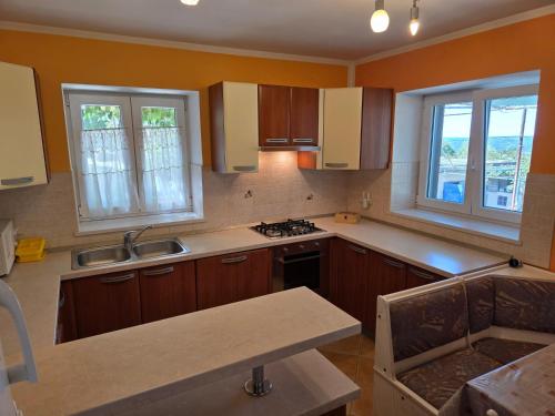 a kitchen with wooden cabinets and a sink and two windows at Apartman Nina in Stanišovi