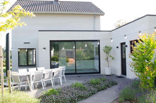 a patio with white chairs and a table at Vakantiewoning Ten Huyze Bucholt met tuinsauna in Bocholt