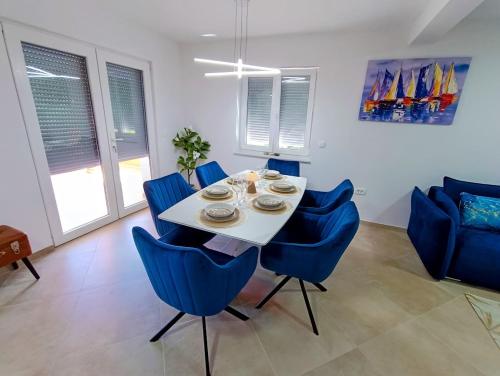 a dining room with a white table and blue chairs at Apartma LANA in Koper