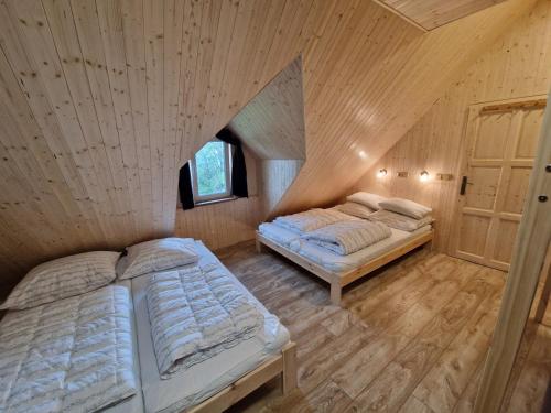 two beds in a room with a wooden ceiling at Horská Chata Hříbek in Benecko