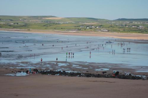 a group of people in the water at a beach at Lios NaMara in Lahinch