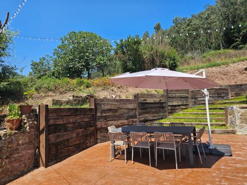a table and chairs with an umbrella on a patio at Ven al Paraiso! Amanece en Miravalles in Villaviciosa