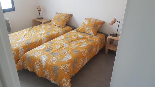 a bedroom with two beds with orange comforter at Maison récente pour vacances en Charente-Maritime in Saint-Agnant