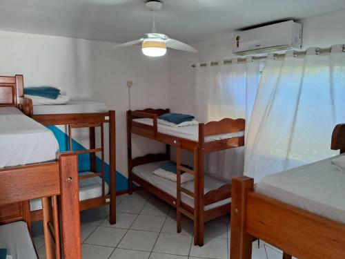 a room with three bunk beds and a ceiling fan at Floripa Surf Hostel in Florianópolis