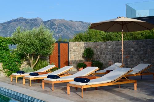 a row of lounge chairs and an umbrella next to a pool at Diamonte Villas Collection in Tivat