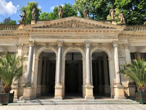 a large stone building with columns and statues at Boutique Apartment Owned by Emperor Peter The Great With 2 Balconies & Jacuzzi in Karlovy Vary