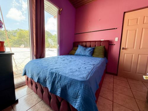 a bedroom with a bed with a pink wall at Casa Vale in Paquera