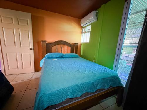 a bedroom with a bed with blue sheets and a window at Casa Vale in Paquera