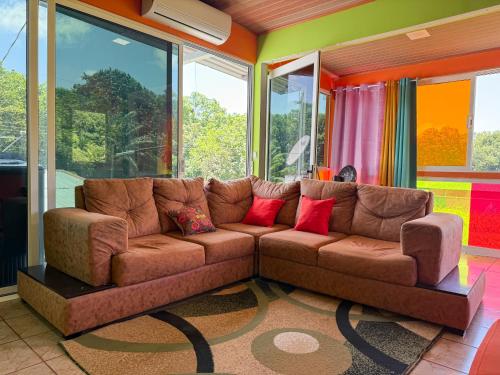 a living room with a brown couch with red pillows at Casa Vale in Paquera