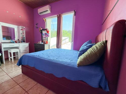 a bedroom with a bed with purple walls and a window at Casa Vale in Paquera