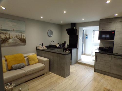 a living room with a couch and a kitchen at 4 The Dome, Barton on sea - Where Comfort Meets the Coast in Barton on Sea
