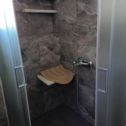 a bathroom with a shower with a stone wall at Comfort house in Ermoupoli