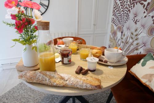 a table with breakfast foods and drinks on it at Nid normand en bâtisse 1620 - Calme & hyper centre in Pont-Audemer