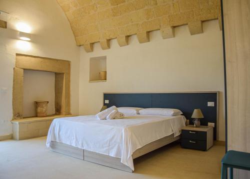 a bedroom with a large white bed and a mirror at Agriturismo Masseria Sbotta in SantʼAndrea