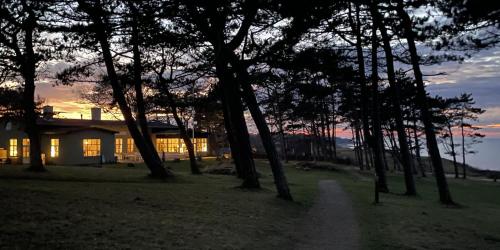 a house with trees in front of a sunset at Gilbjerg Strandhotel in Gilleleje