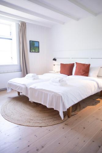 a large white bed in a room with a wooden floor at Gilbjerg Strandhotel in Gilleleje