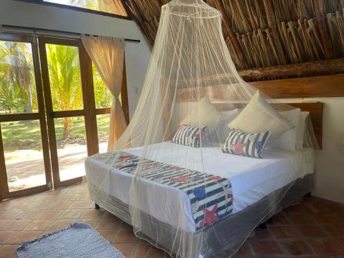 a bedroom with a bed with mosquito net at Casa Arrecife San Bernardo del Viento in San Bernardo del Viento