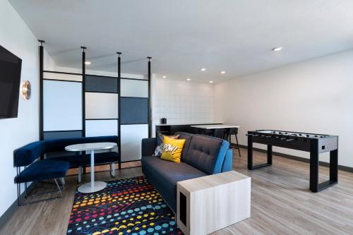 a living room with a couch and a ping pong table at Aloft Omaha West in Omaha