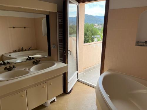 une salle de bain avec deux lavabos, une baignoire et un miroir dans l'établissement charming villa with pool, à Bastelicaccia
