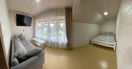 a circular room with a couch and a bed and a window at Mini Cottage in Yablunytsya