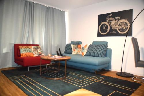 a living room with a blue couch and a red chair at GraceHomes - Garage, Ventilator, Free Coffee, Airport, Messe, Stuttgart, WiFi up to 6 Guests in Leinfelden-Echterdingen