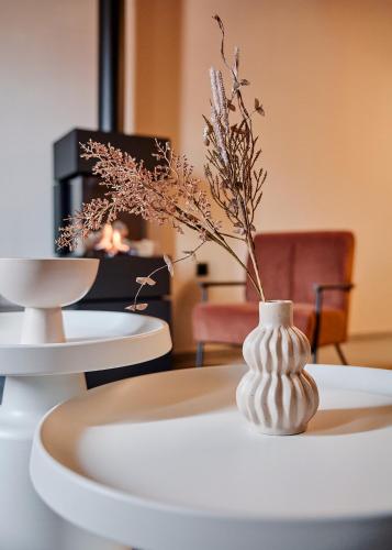 a white vase with flowers in it on a table at Reve Suites Ioannina in Ioannina