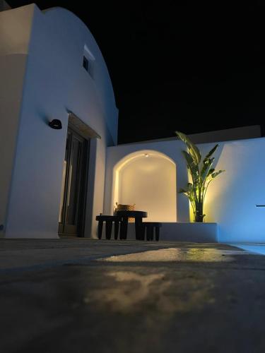 a building with a table and a potted plant at Koniko Santorini Private Pool Villas in Santorini