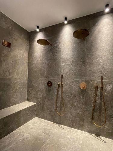 a bathroom with a walk in shower with two shower heads at Koniko Santorini Private Pool Villas in Santorini