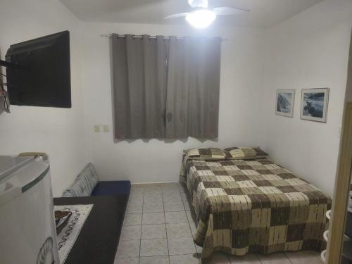 une chambre avec deux lits et une télévision à écran plat dans l'établissement KitNet confortável com ótima localização no Cento de Guarapari, à Guarapari
