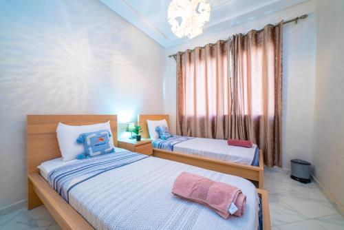 a bedroom with two beds and a window at Appart familial climatisé, spacieux et raffiné avec vue sur jardin - Proche de l'aéroport, Marjane et de la forêt" in Fès