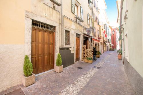 an empty alley with a building with brown doors at Nido sui Tetti di Riva del Garda - Happy Rentals in Riva del Garda