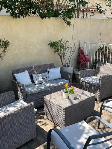 a patio with wicker chairs and couches and tables at Chambre privé avec piscine ,parking et cuisine prive in Marseille
