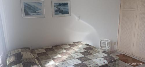 a bedroom with a bed and two pictures on the wall at Flat no coração de Guarapari,150 metros da praia com vista encantadora in Guarapari