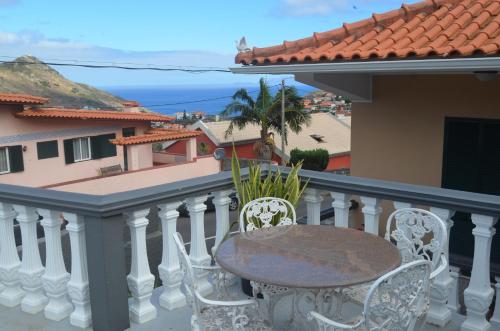 Una mesa y sillas en un balcón con vista al mar. en Vista dos Encantos, en Machico