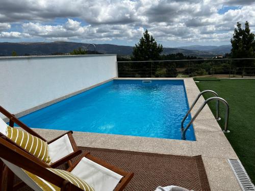 a swimming pool on a patio with two chairs at Moradia Vila Golfe in Amarante