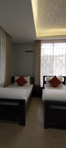 two beds in a room with a window at Nguchiro Palace Hotel in Moshi