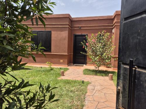 a house with a black door and a yard at Villa-l-arganier - Piscine - Sans vis-à-vis in Eddir