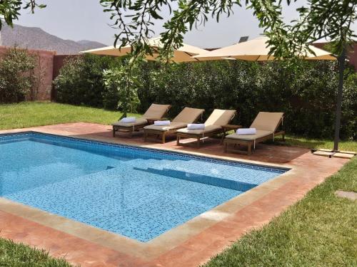 a swimming pool with lounge chairs and an umbrella at Villa-l-arganier - Piscine - Sans vis-à-vis in Eddir