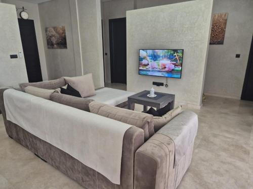 a living room with a couch and a tv at Villa-l-arganier - Piscine - Sans vis-à-vis in Eddir