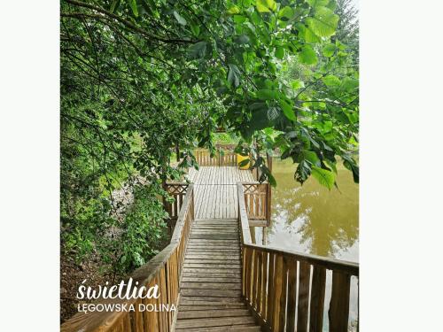 a wooden bridge over a body of water with trees at Łęgowska Dolina in Olecko