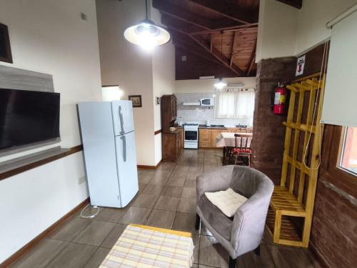 cocina con nevera y silla en una habitación en Jardín del Piltri, en El Bolsón