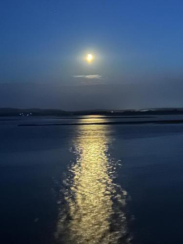 a full moon rising over the water at night at Unobstructed Sea Views , Rockley Park , Poole in Lytchett Minster