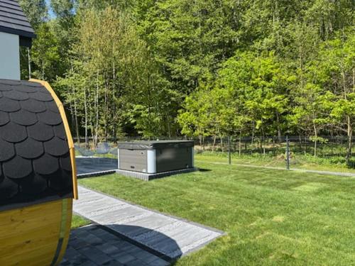 a backyard with a stove in the grass at Domek z Sauną i Jacuzzi Leśne SPA 