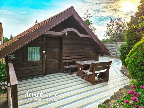 a small wooden cabin with a bench on a deck at Łęgowska Dolina in Olecko