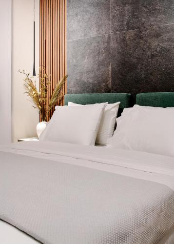 a white bed with white pillows and a green headboard at Reve Suites Ioannina in Ioannina