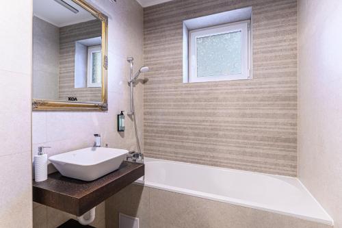a bathroom with a tub and a sink and a mirror at KOA - Sunlight Apartment in Braşov