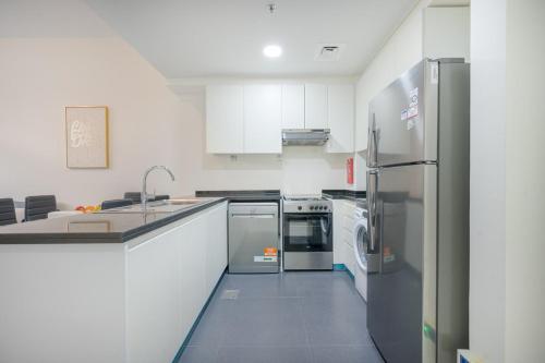 a kitchen with white cabinets and stainless steel appliances at Quickstay holiday homes1BHK Retreat Peaceful & Bright in Dubai